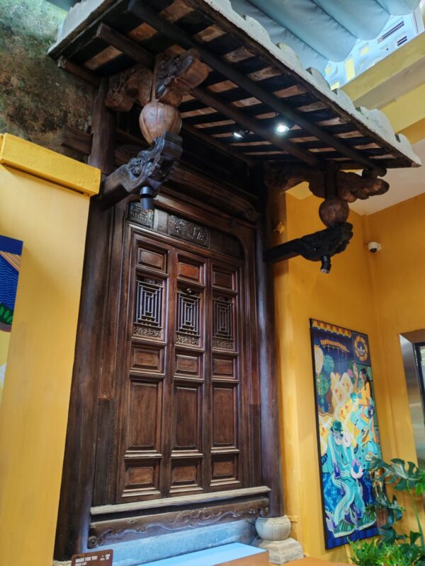 Carved antique wooden door and yellow wall at the adidas store in Hoi An