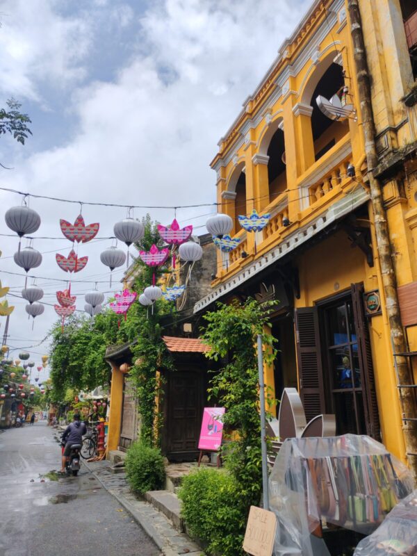 Two-storey yellow heritage house of the adidas store in Hoi An under strings of lanterns