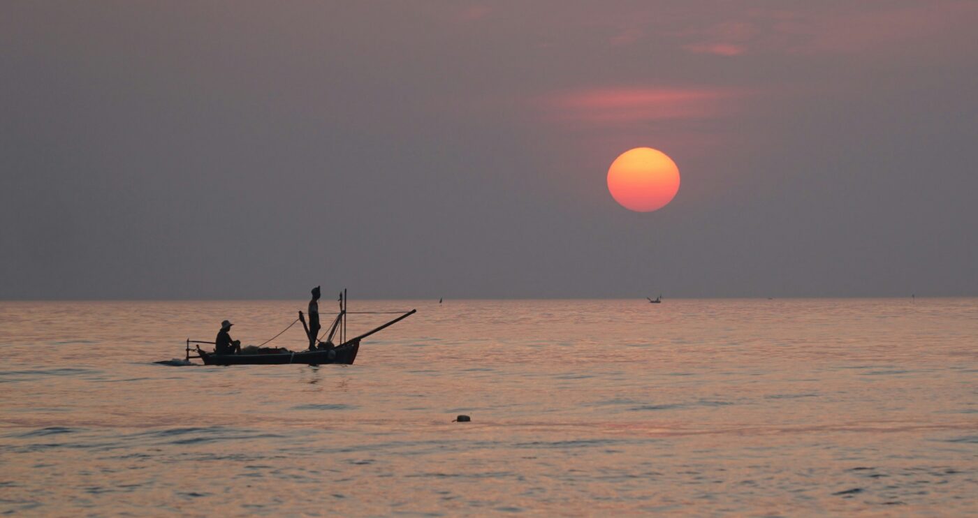 Sunset over the sea with a small fishing boat