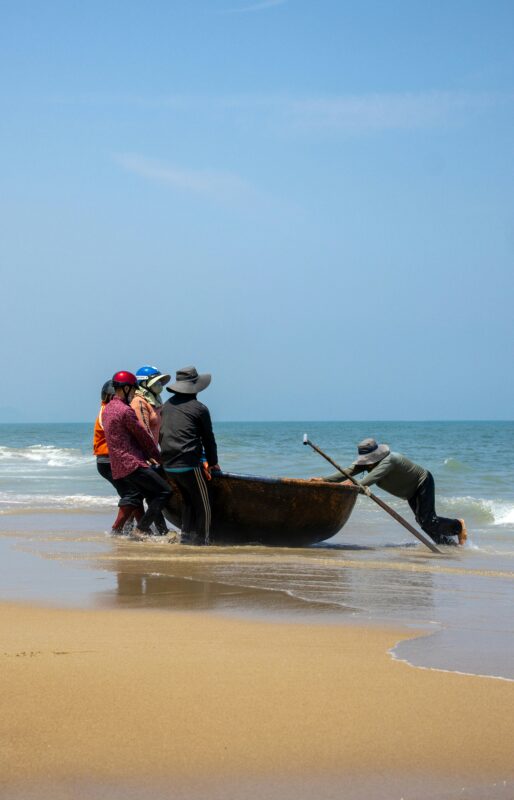 Fishermen pulling a round basket boat onto the beach